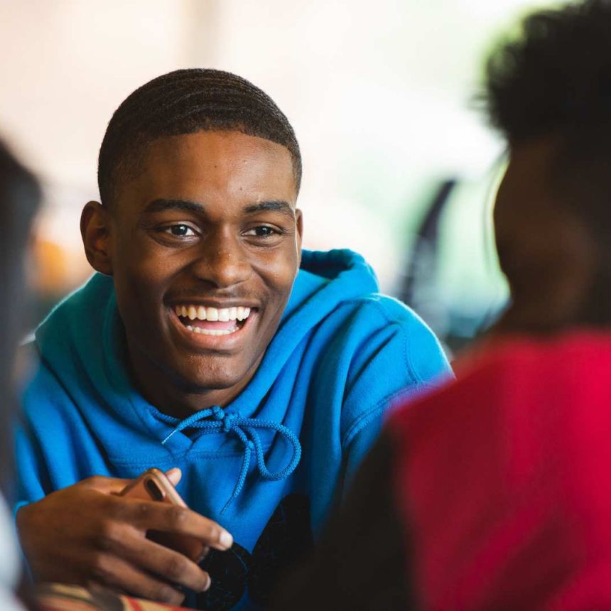 student smiling while listening to other students in foreground