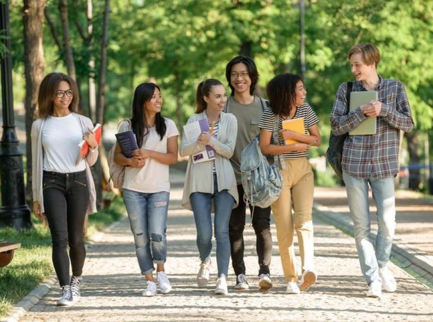 Group of college students walk along a tree-lined pathway.