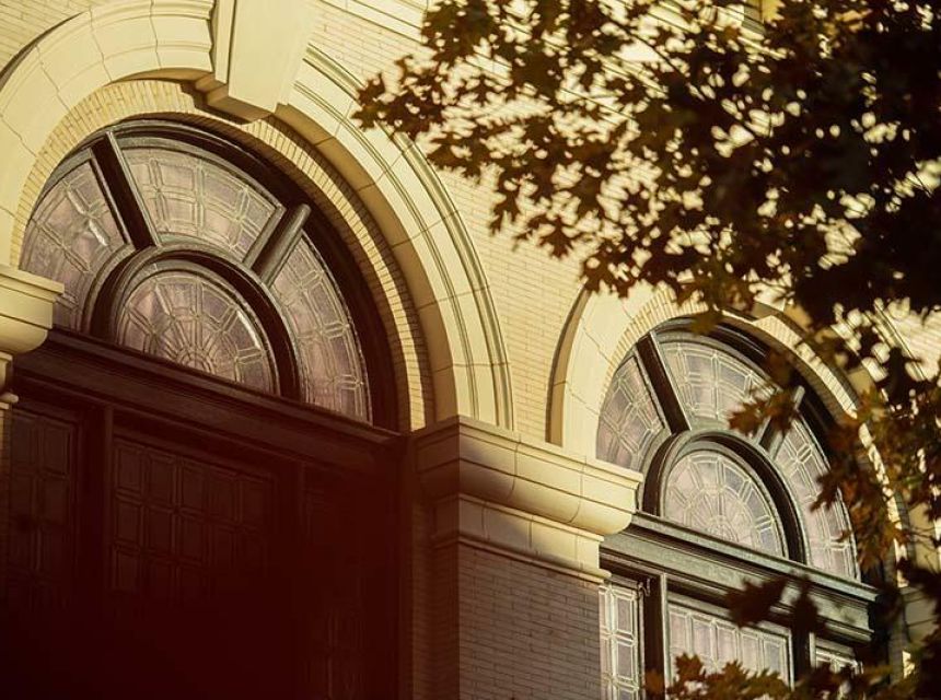 two arched windows with tree branch in foreground
